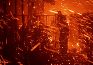 A man uses a garden hose to try to save his home from wildfire in Granada Hills, California, on 11 October 2019. Photograph: Michael Owen Baker/AP