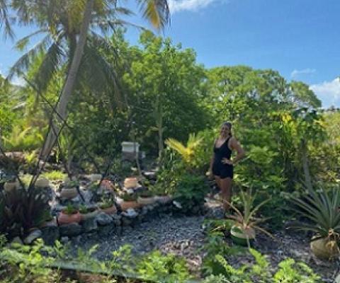 Kamoka Pearl co-owner Celeste Brash stands in front of a portion of the large garden that helps feed the farm crew. In soil made from bird droppings and coconut husks, they're attempting to grow everything from arugula and pineapples to taro and carrots in old broken buoys — all in an effort to be as self-sufficient as possible. Credit - Ashley Westerman/Courtesy The World