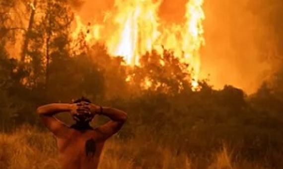 A resident watches a wildfire on Evia island, Greece, as the region endures its worst heatwave in decades, which experts have linked to the climate crisis. Photograph: Angelos Tzortzinis/AFP/Getty Images