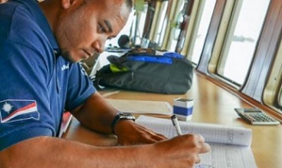 Fisheries officer Beau Bigler crosschecks ship documentation as a fishing vessel seeks authorisation to use the port of Majuro. Photo: Francisco Blaha.