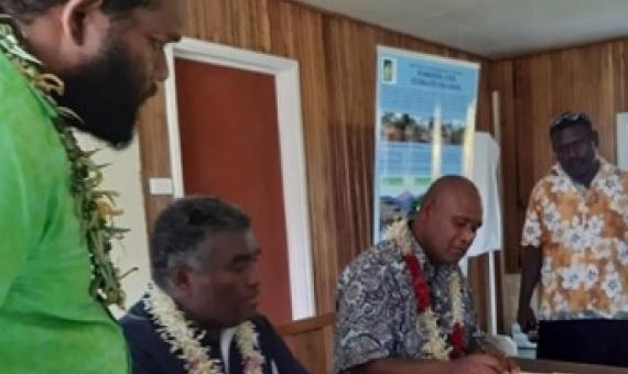 Minister Togamana signing the certificate of declaration flanked by staff of the Environmental Division MECDM and a Community elder.
